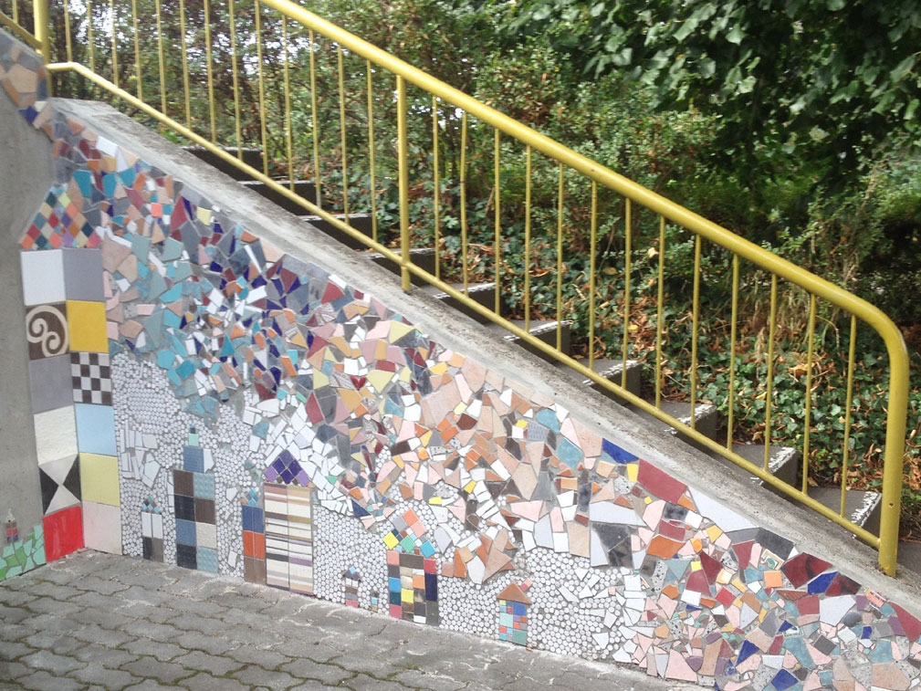 Außentreppe mit buntem Mosaik aus Fliesen und Glasscherben.