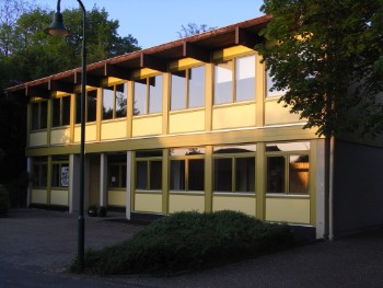 Modernes, zweistöckiges Gemeindezentrum mit großen Fenstern.