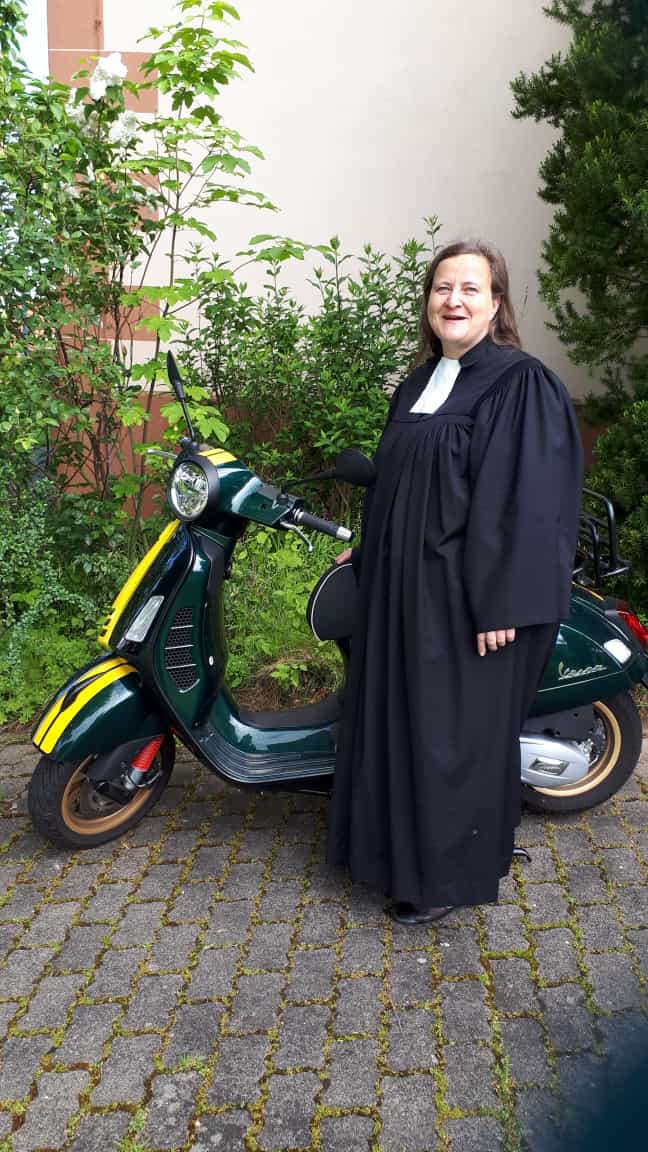 Pfarrerin vom Kooperationsraum Kurhessische Riviera mit grünem Motorroller.