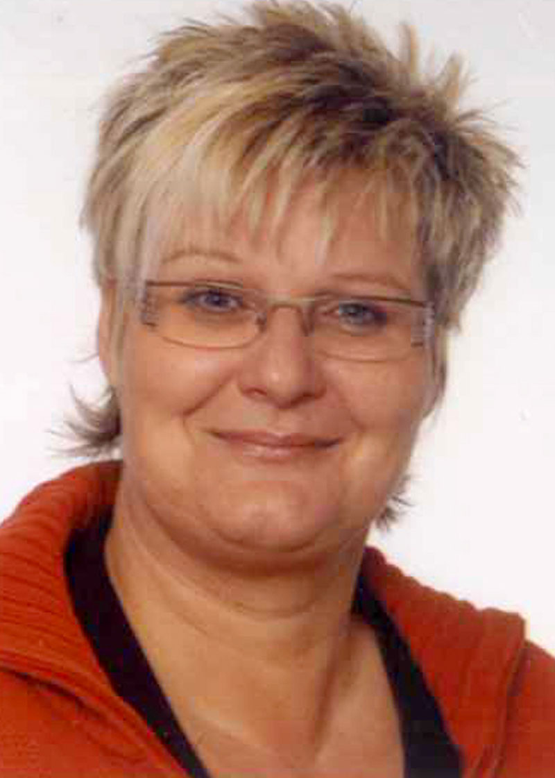 Porträt einer lächelnden Frau mit kurzen blonden Haaren.