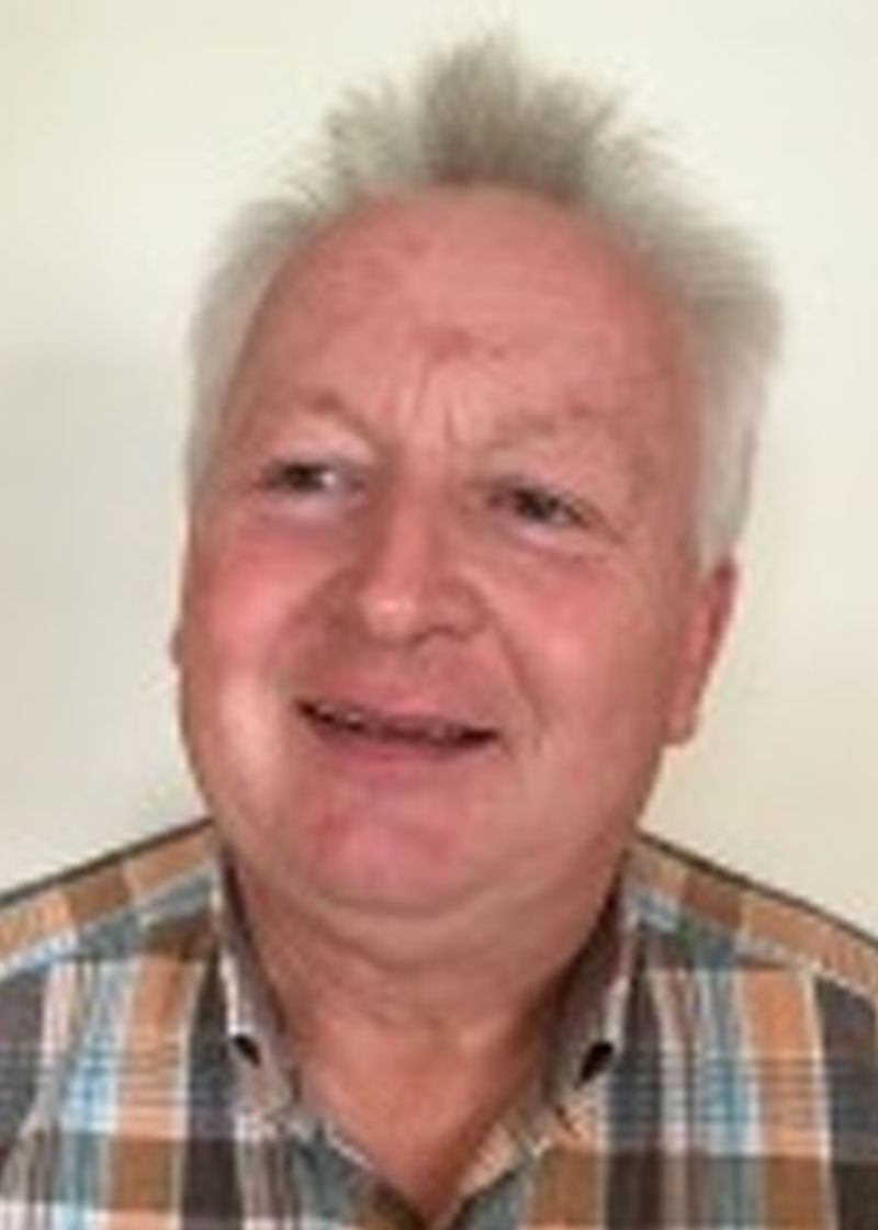 Porträt eines Mannes mit weißem Haar im karierten Hemd.